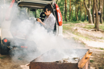 Obraz premium bbq on fire. woman sitting in car trunk. car travel concept