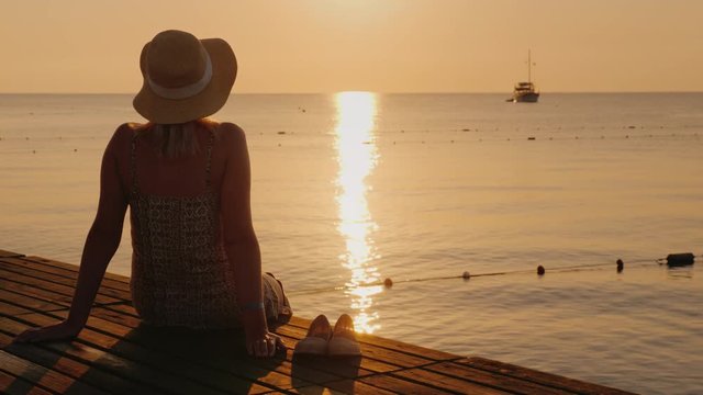 Silence and pacification in the early morning on the sea pier, the girl enjoys loneliness