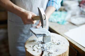 High angle close up shot of unrecognizable tile worker holding hammer  breaking piece of marble to...