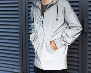 Modern materials in the fashion industry. Men's youth street fashion. Windbreaker from the rain. A man is posing in a fashionable black jacket made of new technological materials. Part of the body. © superlime