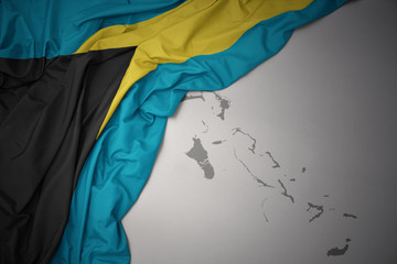waving colorful national flag and map of bahamas.