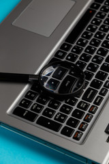 Laptop computer with magnifying glass on blue background, concept of search. Internet security conceptual image. Close up