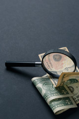 Magnifying glass and money on black background. Paper currency. Looking For Money. Concept of search. Close up