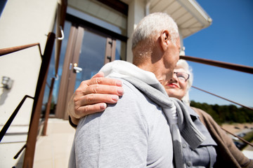 Low angle portrait of modern senior couple embracing standing outdoors in sunlight