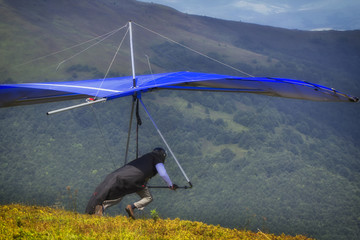 Hangglider take-off An athlete with a blue hang-glider prepares to start