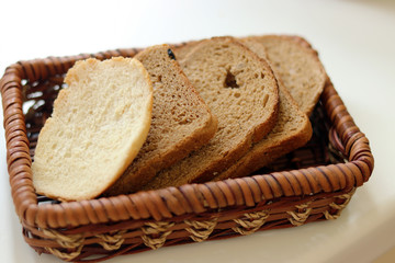 chopped toasts white and black bread in a straw basket. bread from wheat and barley