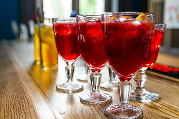 on the bar stand glasses with drinks of red and yellow with ice.