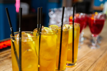 on the bar stand glasses with drinks of red and yellow with ice.