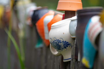 Row of ceramic jugs on a wooden fence in the village outdoor