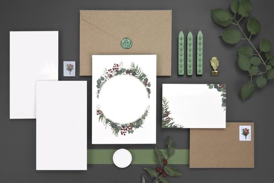 Blank rustic fall wedding invitation flat lay. Wedding invitation cards with green leaves, red flowers, on ivory paper. Complete with belly band, green leaf wax seal, custom insert card, and RSVP card