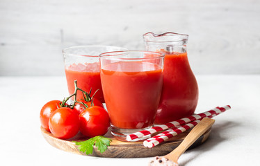 Tomato juice with fresh tomatoes, parsley, sea salt and pepper on light grey background. Vegetable drink.