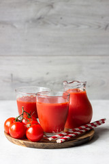 Tomato juice with fresh tomatoes, parsley, sea salt and pepper on light grey background. Vegetable drink.