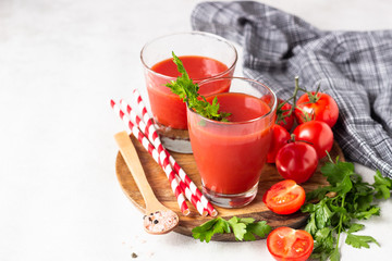 Tomato juice with fresh tomatoes, parsley, sea salt and pepper on light grey background. Vegetable drink.