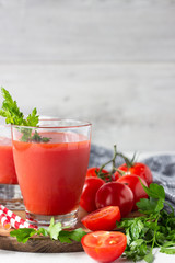 Tomato juice with fresh tomatoes, parsley, sea salt and pepper on light grey background. Vegetable drink.