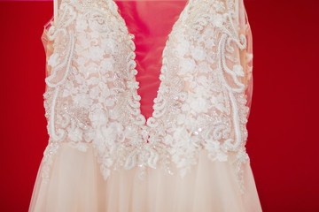 Cream wedding dress close-up, lace and beads. Red background