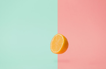 half lemon levitate in air on pink and green backgrounds.