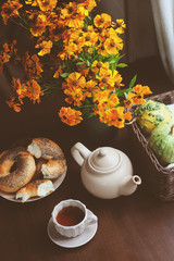 cozy autumn breakfast on table in country house. Hot tea, bagels and flowers on dark brown table