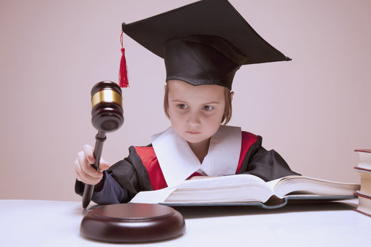 Portrait of serious child girl judge (lawyer) makes a decision. Humorous photo.