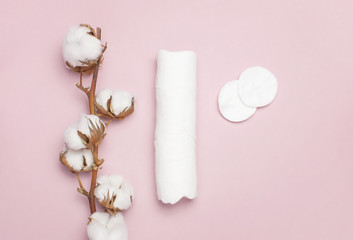 Spa concept. Flat lay background with branch of cotton plant, cotton pads. Cotton Cosmetic Makeup Removers Tampons. Hygienic sanitary swabs on the pink background Top view