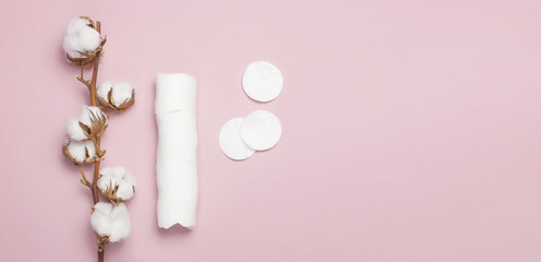 Spa concept. Flat lay background with branch of cotton plant, cotton pads. Cotton Cosmetic Makeup Removers Tampons. Hygienic sanitary swabs on the pink background Top view