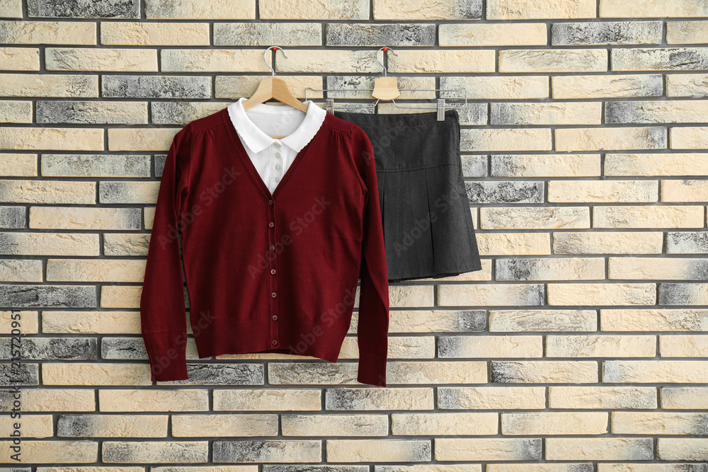 Wall mural School uniform for girl hanging on brick wall