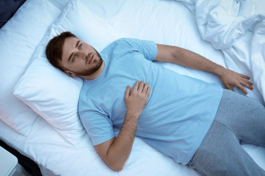 Young man lying in bed at night. Sleep disorder