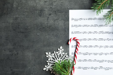 Flat lay composition with candy cane, fir branches and music sheet on table. Christmas songs concept