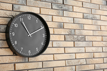 Stylish clock on brick wall. Time concept