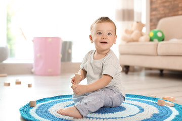 Adorable little baby playing with wooden blocks at home