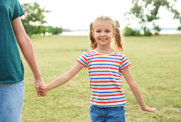 Fototapeta premium Woman holding hands with her child outdoors. Happy family