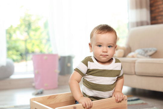 Adorable little baby in wooden cart at home