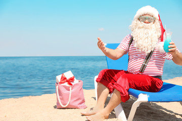 Obraz premium Authentic Santa Claus with cocktail resting on lounge chair at resort