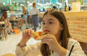 background. beautiful girl sits in a cafe and eats pizza