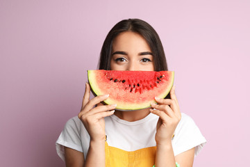 Beautiful young woman posing with watermelon on color background © New Africa