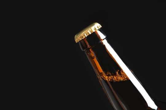 Bottle of tasty cold beer on black background, closeup