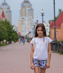 background. beautiful girl walks on the waterfront on a background of tall houses and green trees