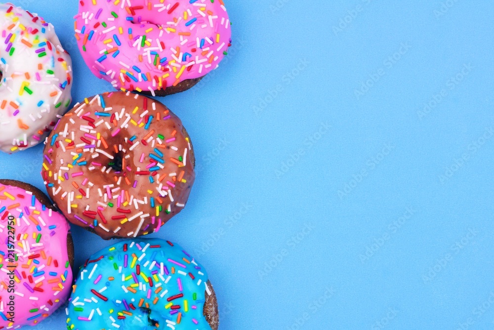 Poster side border of assorted donuts with frosting and sprinkles against a pastel blue background