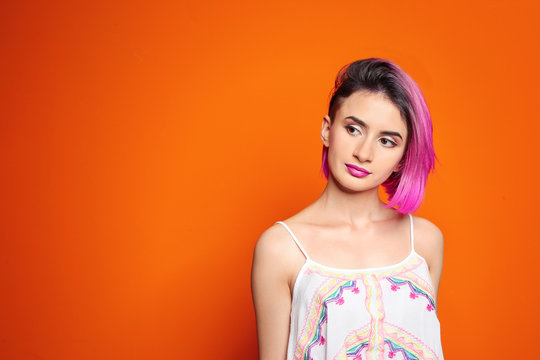 Young woman with trendy hairstyle against color background