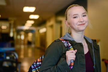 Happy High school student with backpack in school hallway