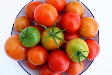 Fresh green and red cherry tomatoes on a white saucer, top view
