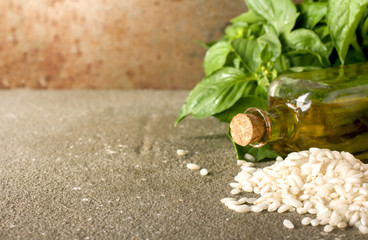 Fresh basil leaves, rice arborio and olive oil on rustic background