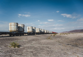 Freight cargo in large white shipping container cylinders being transported via train through the desert of Bolivia