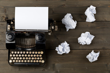 Vintage typewriter top down flatlay shot from above with empty, blank sheet of paper and crumbled...