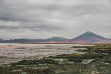 Mountains and a volcano surround to the 'Laguna Colorada' in Bolivia, famous for its red lagoon water and flamingoes