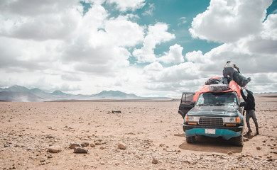 Obraz na płótnie Canvas Two Bolivian tour guides load up the roof-rack of a 4x4 ready for a desert and salt flat tour through Eduardo Avaroa National Park in Bolivia