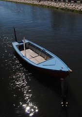 Barco âncorado no rio com luz do sol a espelhar na água