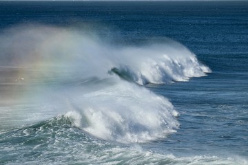 waves in the ocean creating a rainbow 