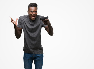 Young african american man holding a gun very happy and excited, winner expression celebrating victory screaming with big smile and raised hands