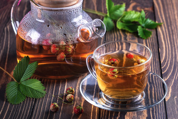 Fruit tea with wild berries in glass cup, on wooden background.Healthy drink with forest strawberry.