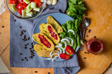 Crispy corn breads slices. Spicy and tasty on plate with green salad leaves, onion rings and tomatoes. Vegan lunch or vegetarian dinner. Healthy food concept.